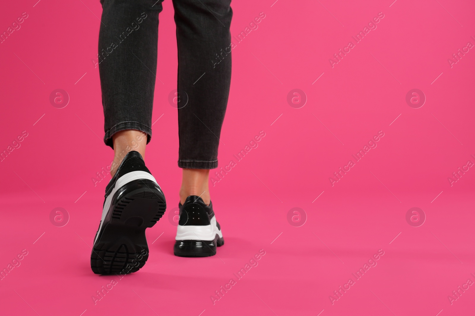 Photo of Woman wearing sneakers on pink background, closeup. Space for text