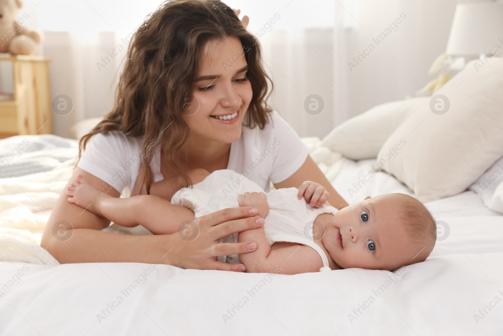 Photo of Happy young mother with her cute baby on bed at home