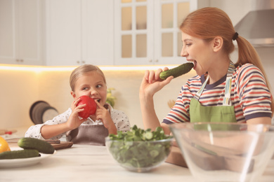 Photo of Mother and daughter cooking salad together in kitchen