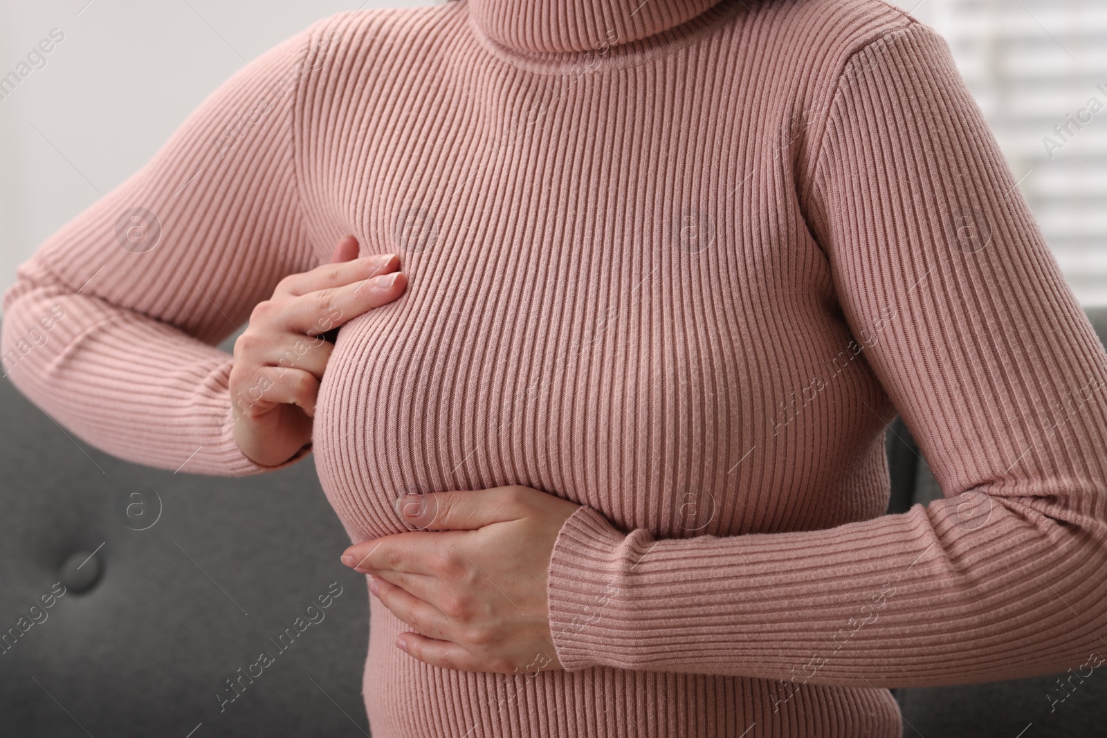 Photo of Mammology. Woman doing breast self-examination indoors, closeup