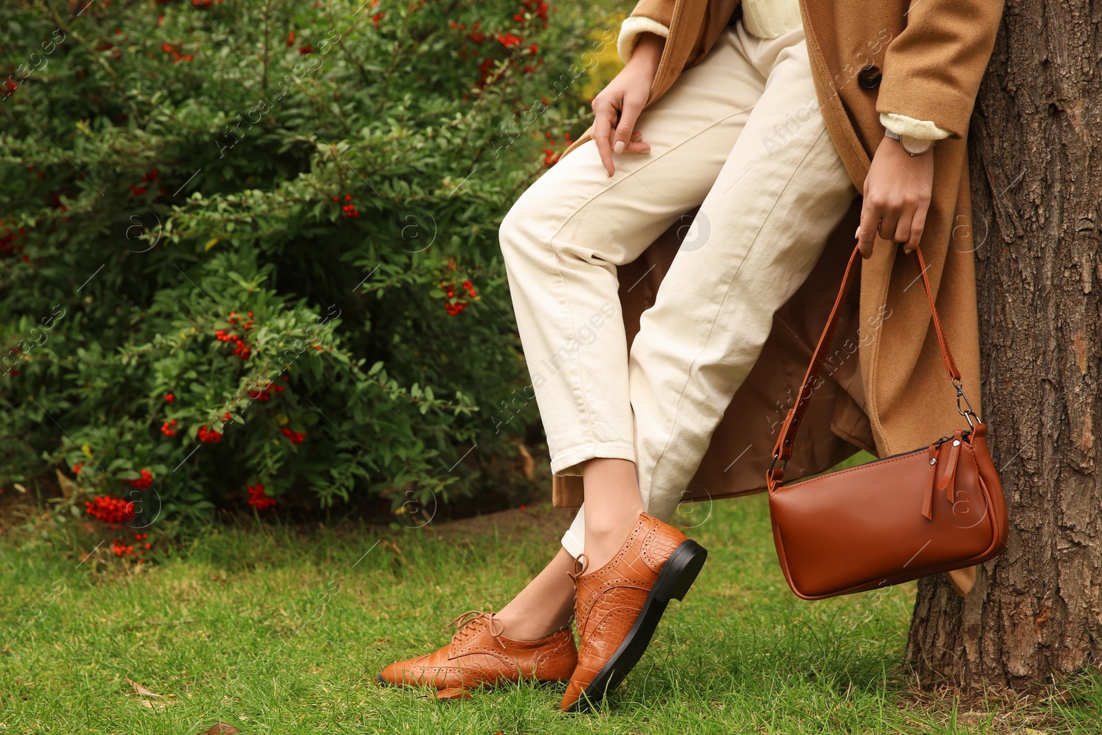 Photo of Stylish woman with trendy leather bag in autumn park, closeup