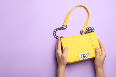 Photo of Woman holding small bag on lilac background, top view. Space for text