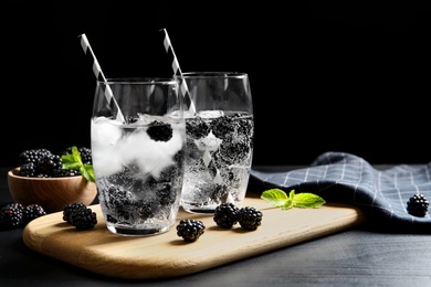 Cold refreshing drink with blackberries on table