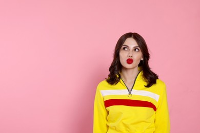 Photo of Beautiful young woman giving kiss on pink background, space for text