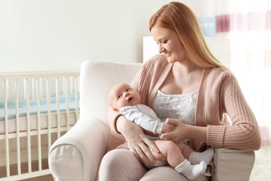 Photo of Happy mother with her baby sitting in armchair at home