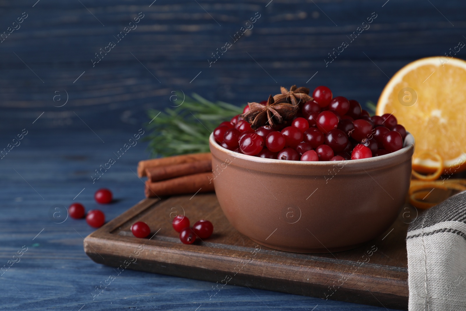 Photo of Fresh ripe cranberries and spices on blue wooden table. Space for text