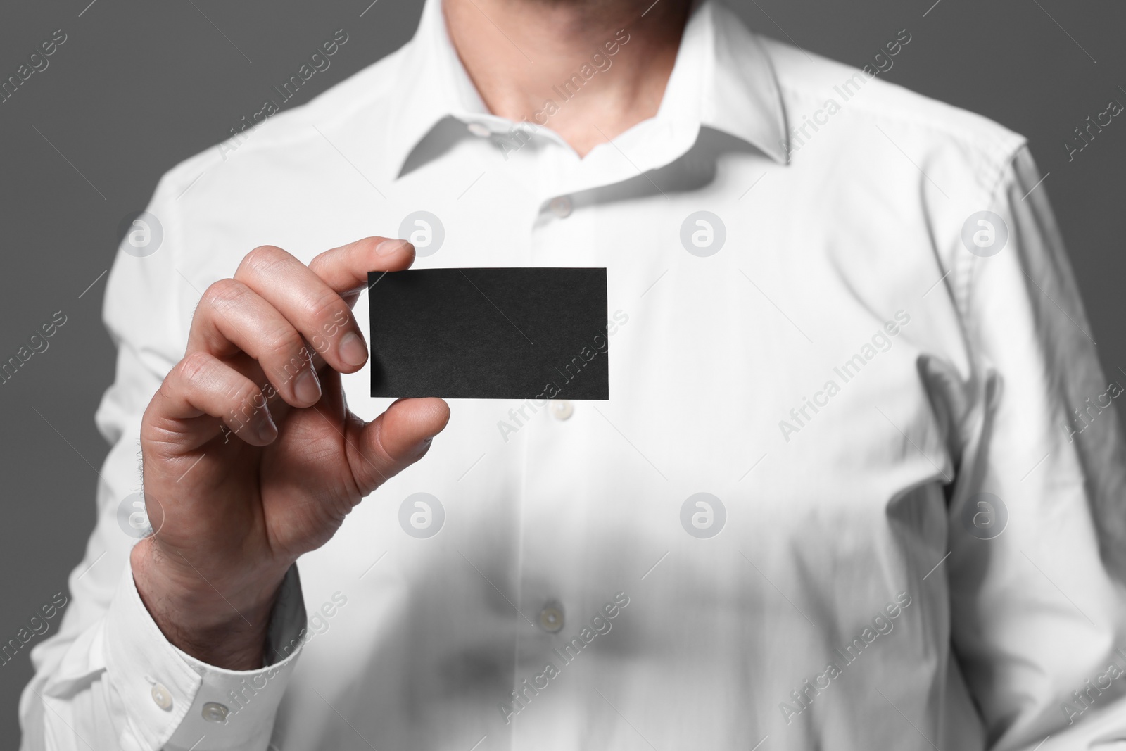 Photo of Man holding blank business card on grey background, closeup