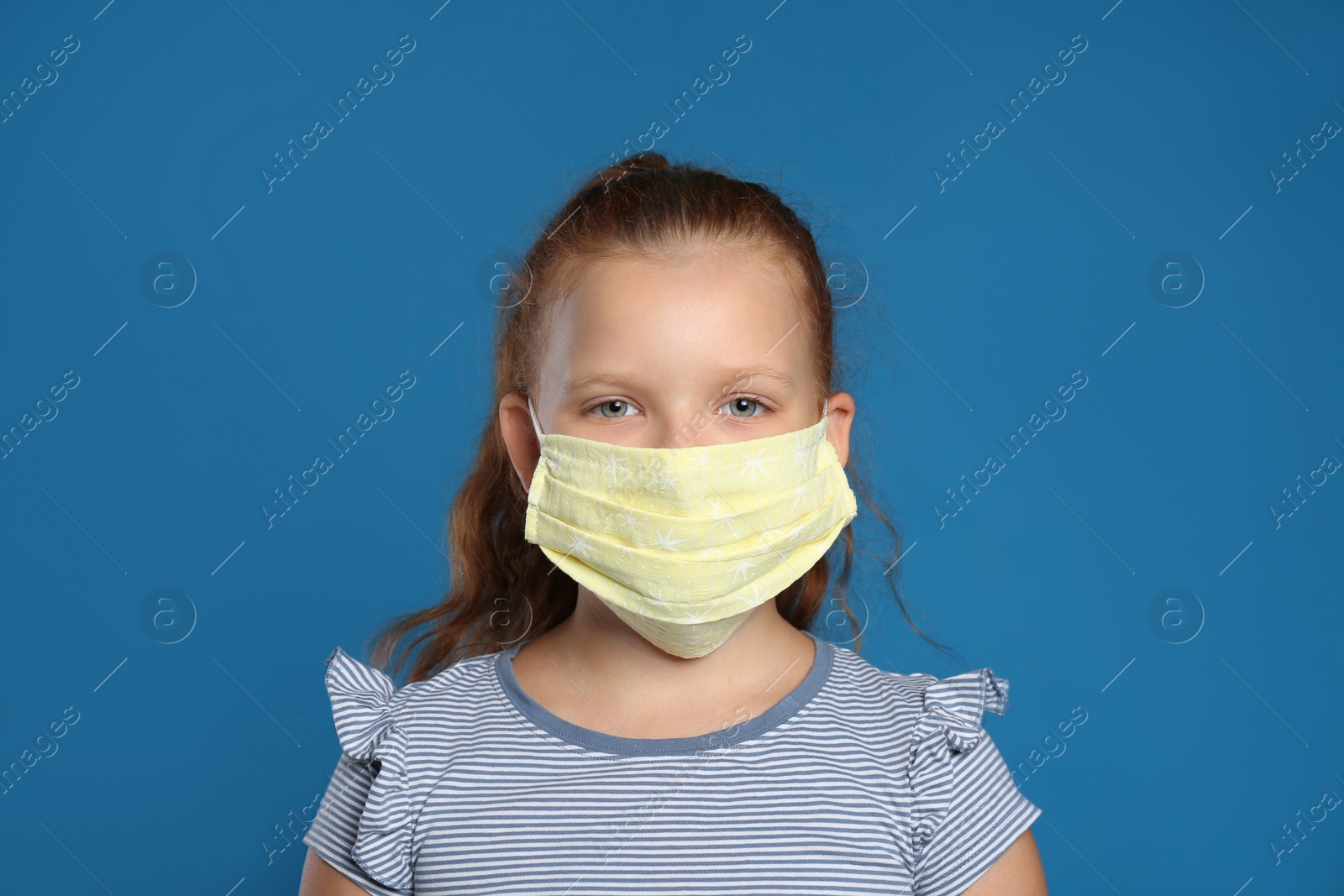 Photo of Preteen girl in protective face mask on blue background