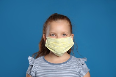 Photo of Preteen girl in protective face mask on blue background