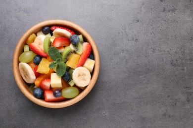 Photo of Delicious fruit salad on grey table, top view. Space for text