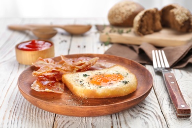 Photo of Plate with fried egg and bacon on wooden background