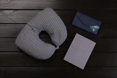 Photo of Striped travel pillow, notebook and wallet with credit card on dark wooden background, flat lay