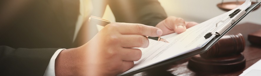 Image of Law and justice. Man working with documents at wooden table, closeup. Banner design