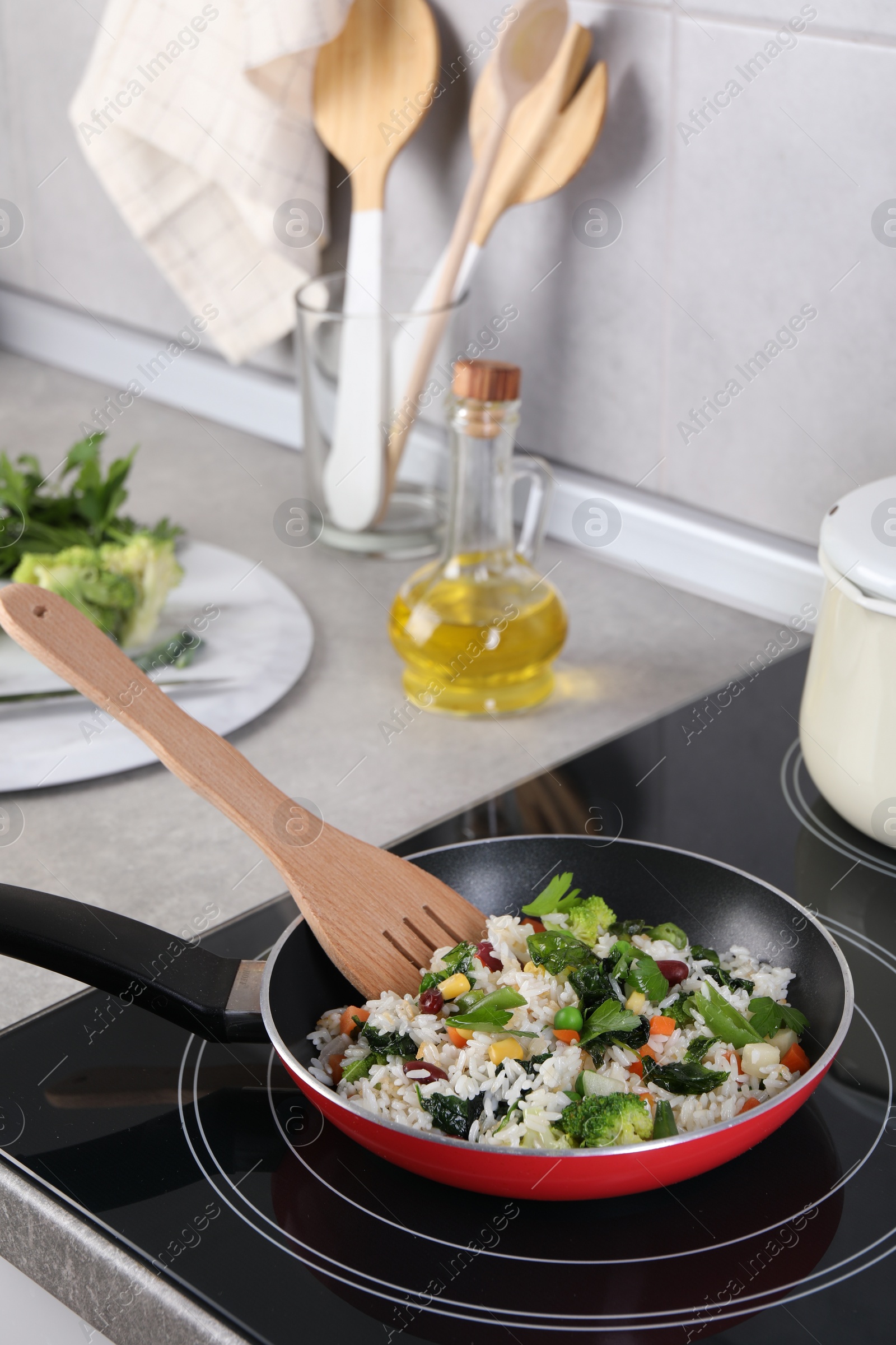 Photo of Frying tasty rice with vegetables on induction stove in kitchen