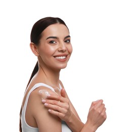 Young woman applying body cream onto her shoulder against white background