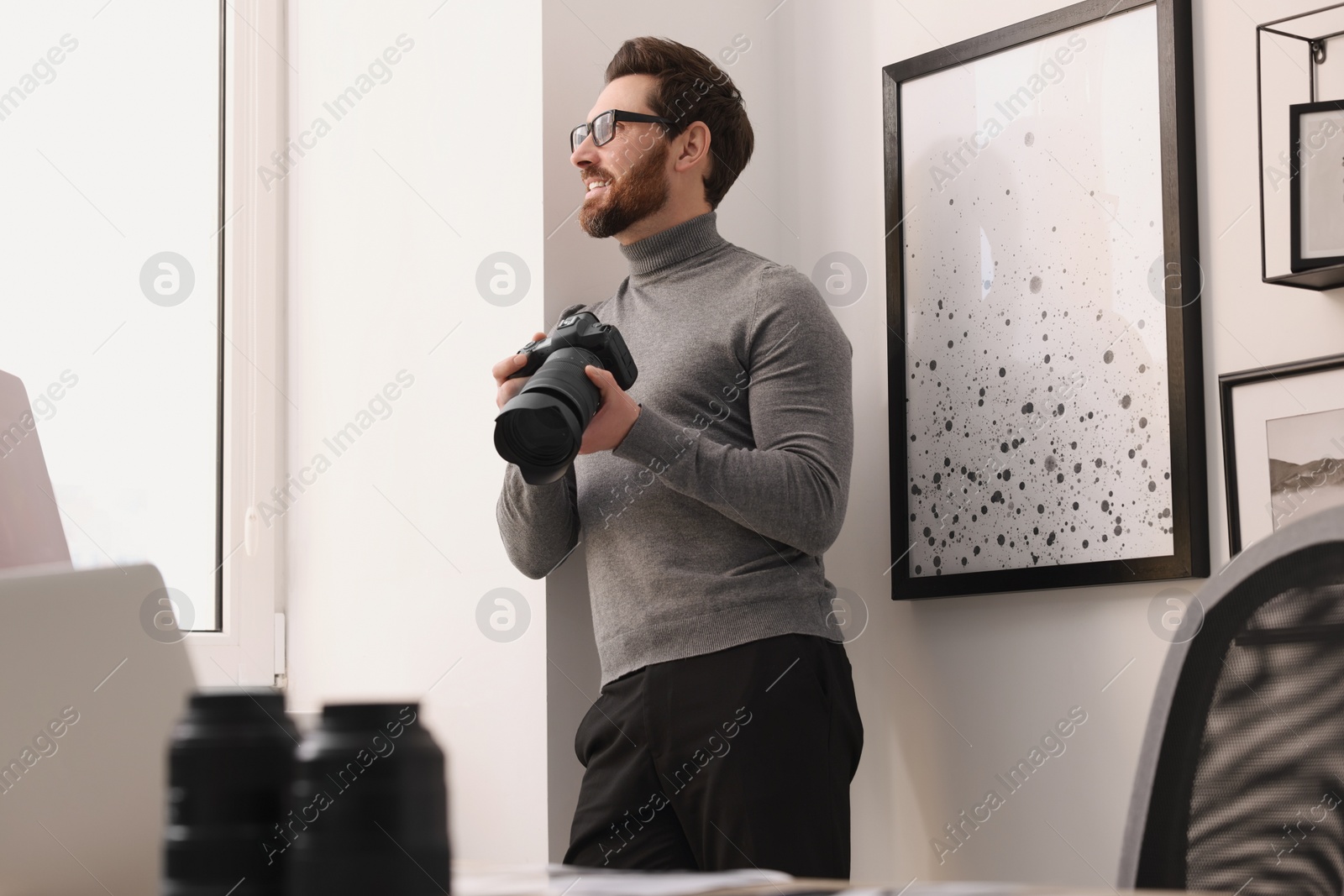 Photo of Professional photographer with digital camera near window indoors