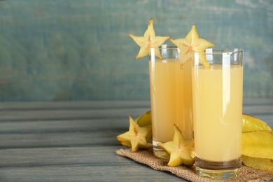 Photo of Delicious carambola juice and fresh fruits on grey wooden table. Space for text