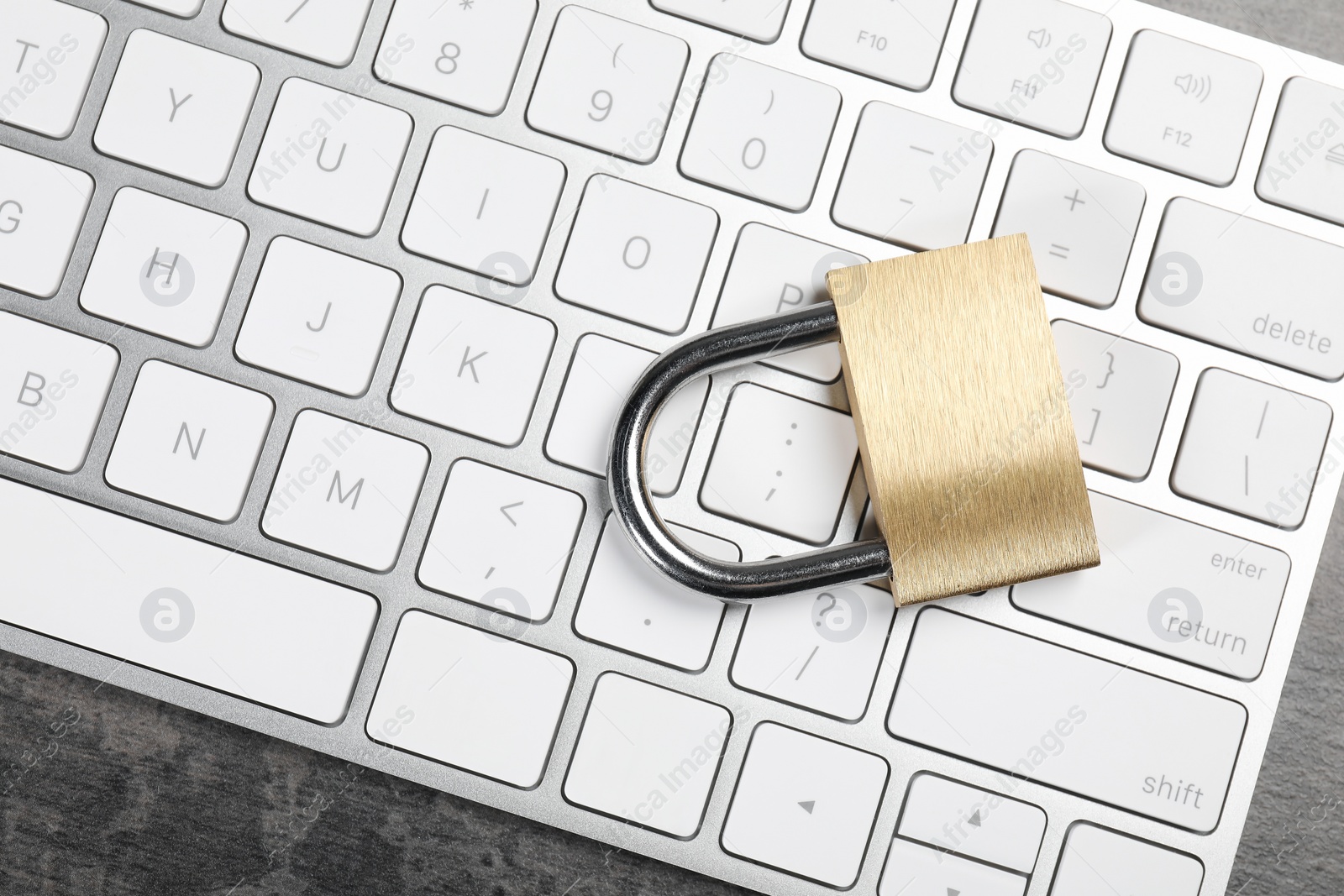 Photo of Cyber security. Metal padlock and keyboard on grey table, top view