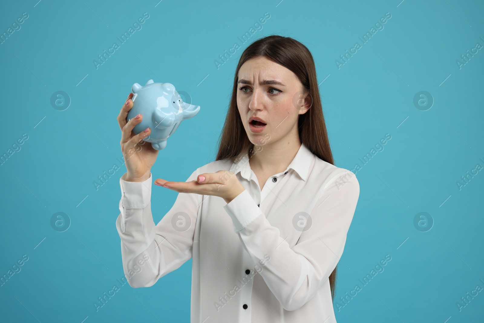 Photo of Sad woman with piggy bank on light blue background