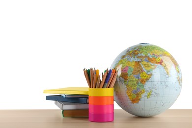 Globe, school supplies and books on wooden table against white background. Geography lesson