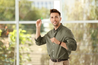 Happy young businessman with green dart indoors