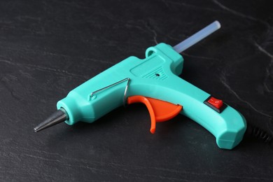 Photo of Hot glue gun with stick on dark grey table