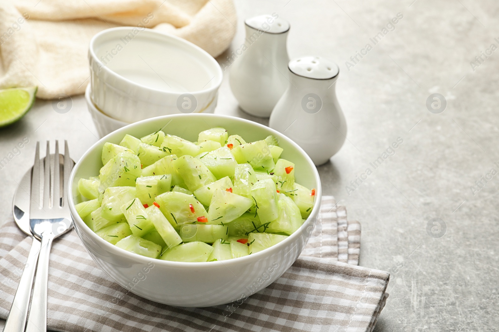 Photo of Delicious cucumber salad in bowl served on table. Space for text