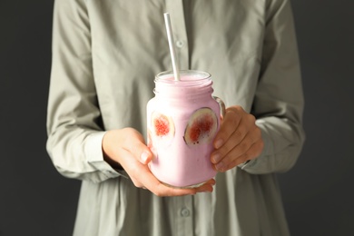 Photo of Woman holding mason jar with fig smoothie on grey background, closeup