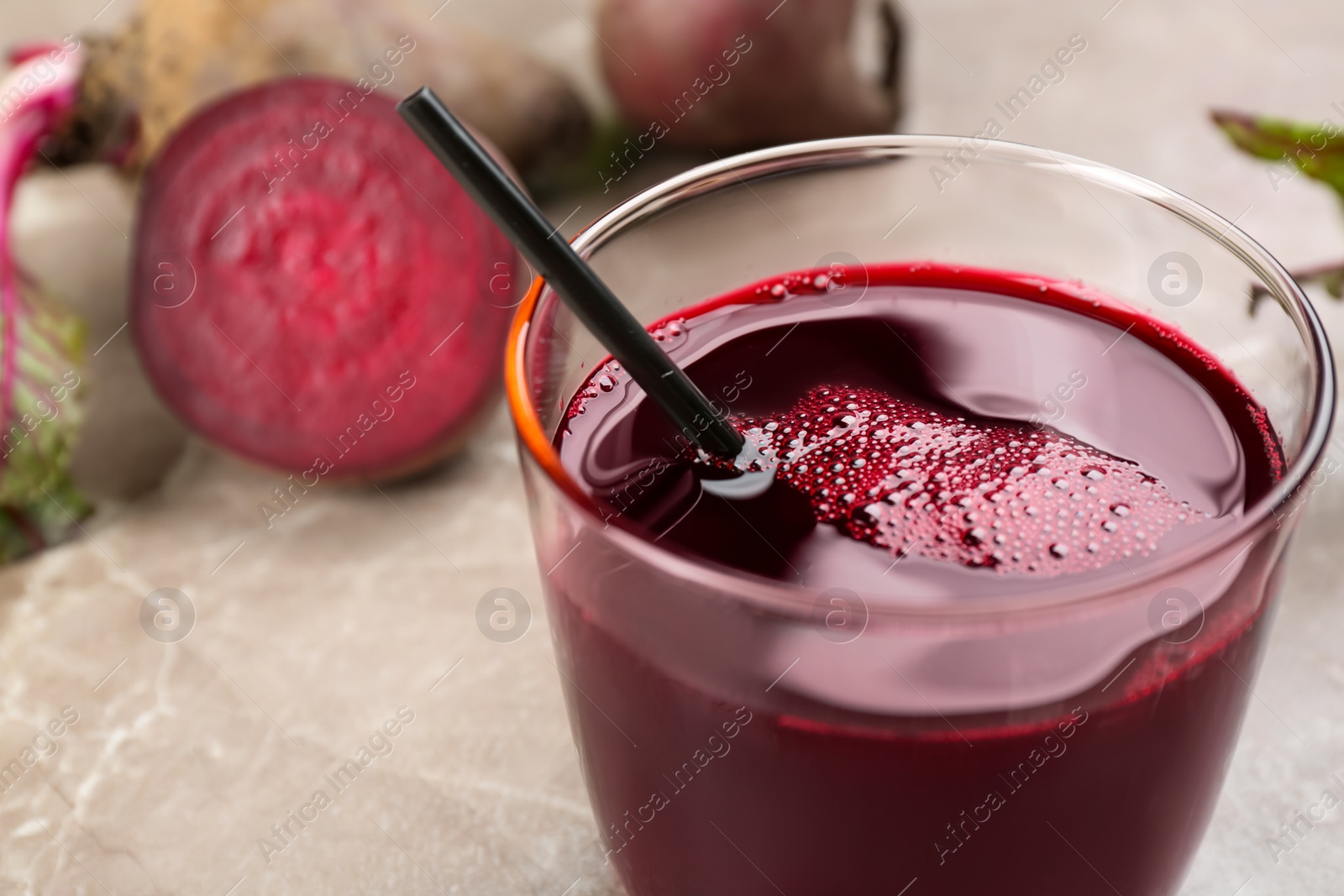 Photo of Freshly made beet juice in glass on grey table, closeup