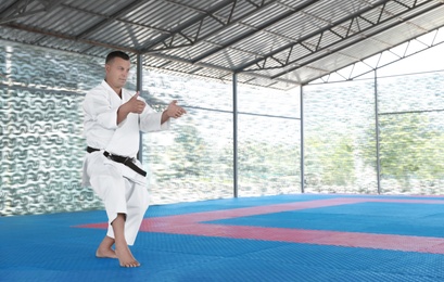 Photo of CHERNOMORKA, UKRAINE - JULY 10, 2020: Mature man practicing karate on training ground, space for text