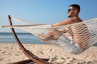 Young man relaxing in hammock on beach