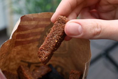 Photo of Woman taking crispy rusk out of package, closeup