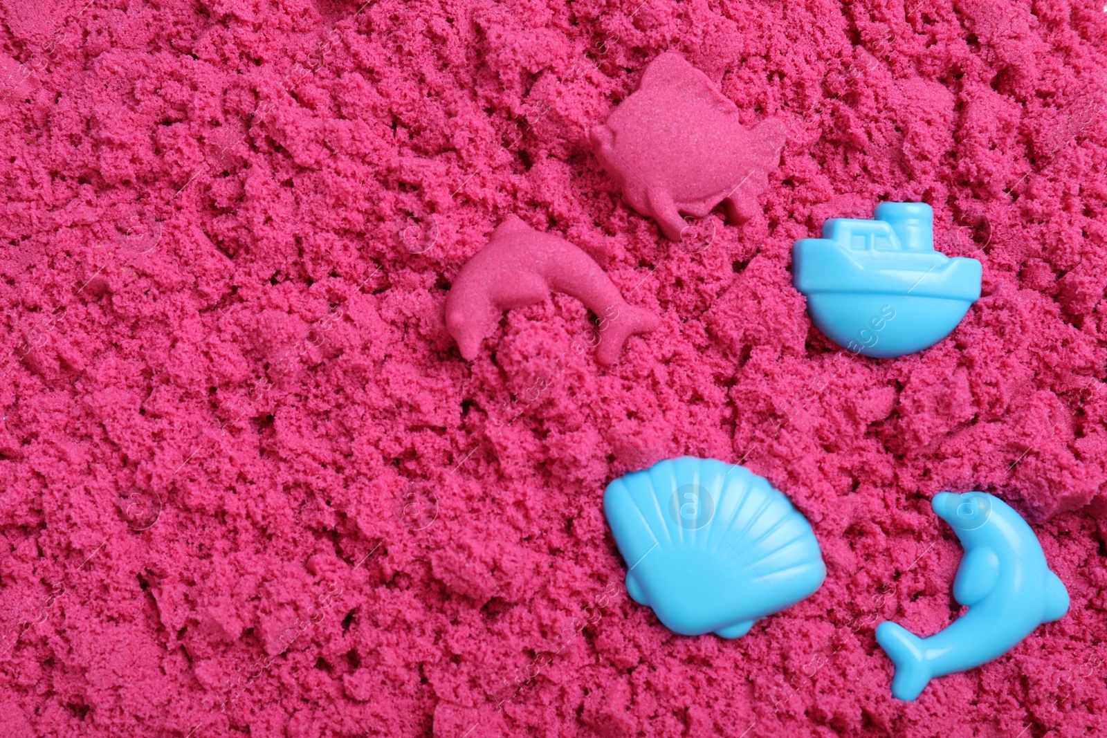 Photo of Toys on pink kinetic sand, flat lay