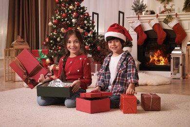 Photo of Happy children opening Christmas gifts on floor at home