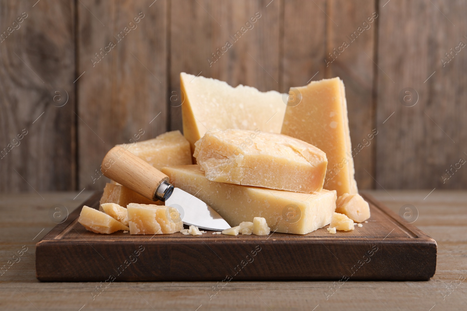 Photo of Delicious parmesan cheese with knife on wooden table