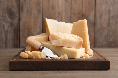 Delicious parmesan cheese with knife on wooden table