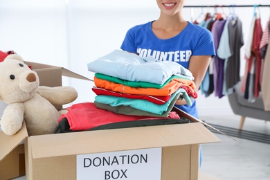 Female volunteer putting clothes into donation box indoors