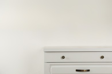 Modern chest of drawers near white wall