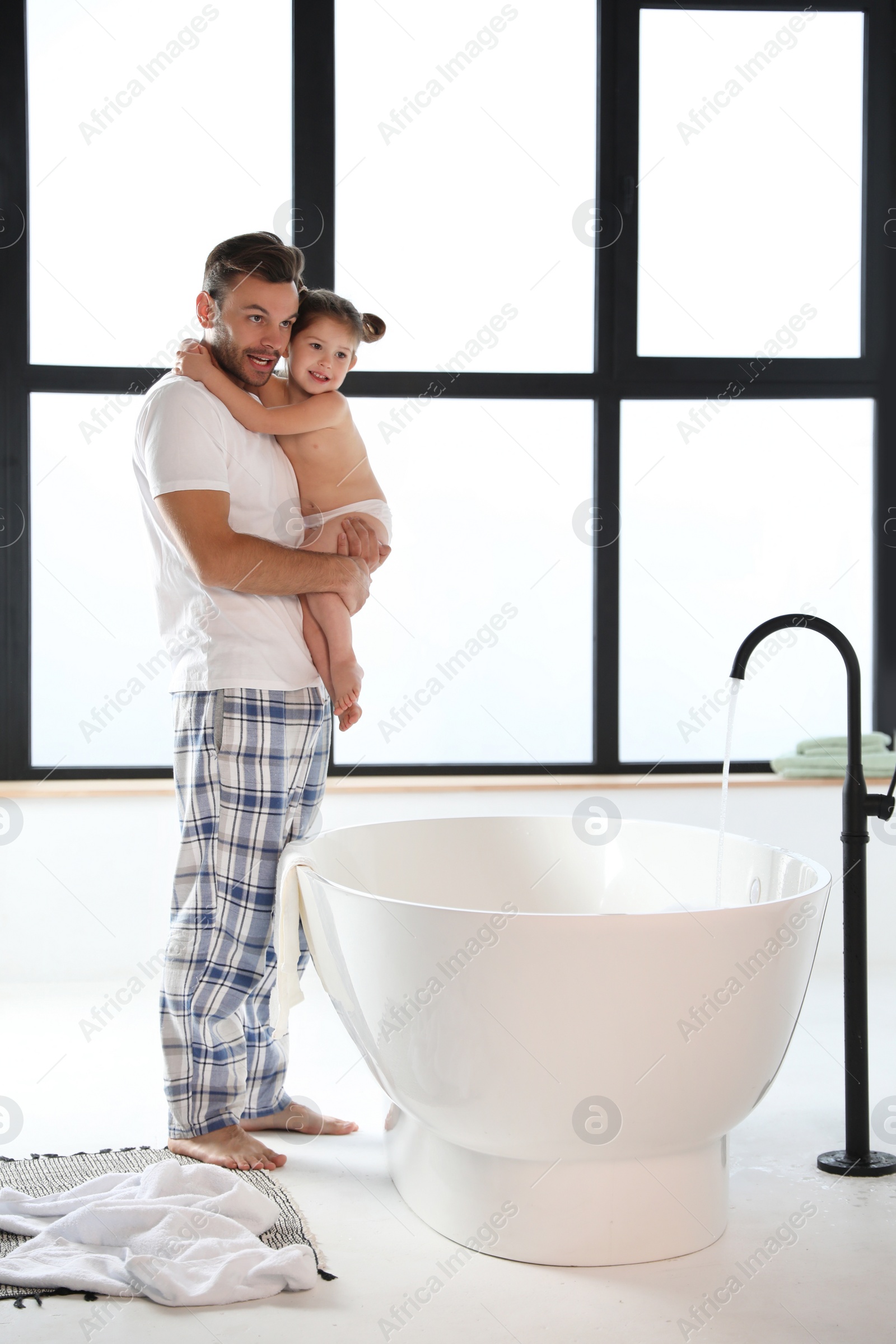 Photo of Young father with cute little daughter in bathroom