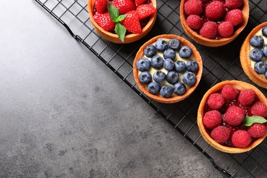 Tartlets with different fresh berries on grey table, top view and space for text. Delicious dessert