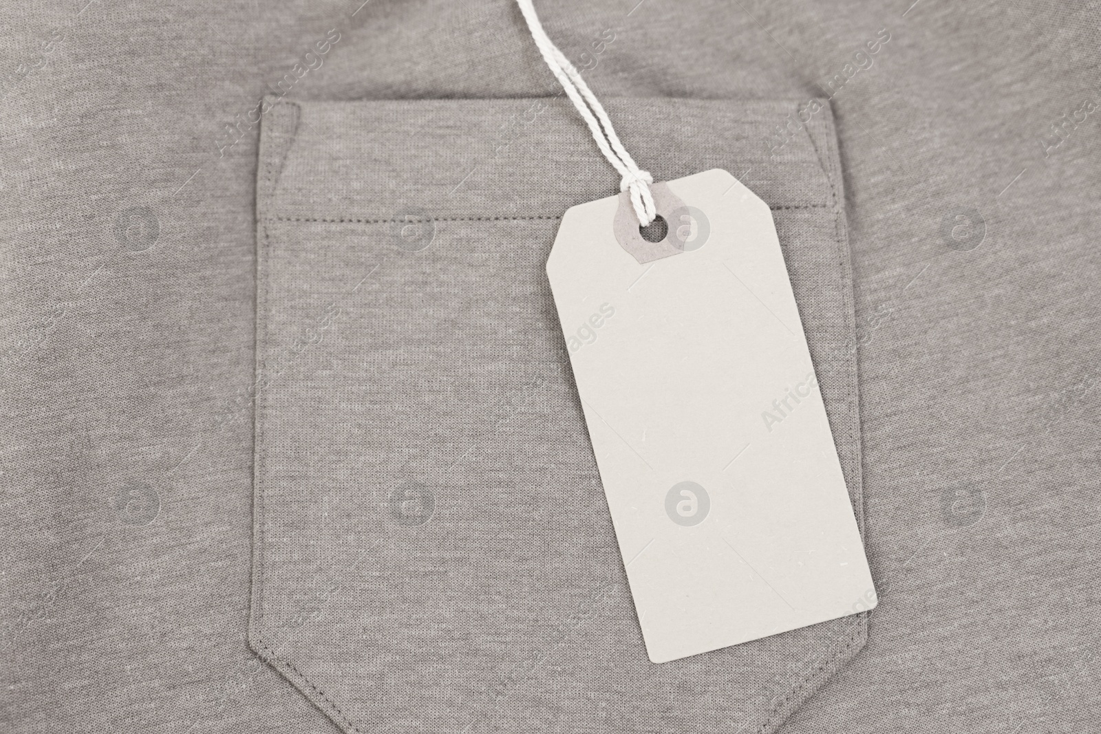 Photo of Cardboard tag on brown garment, top view. Space for text