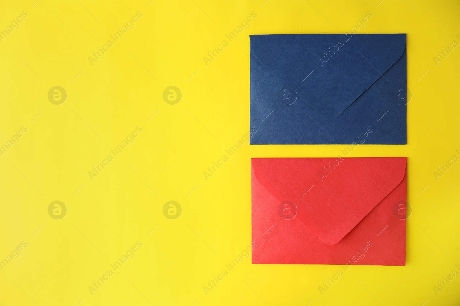 Photo of Colorful paper envelopes on yellow background, flat lay. Space for text
