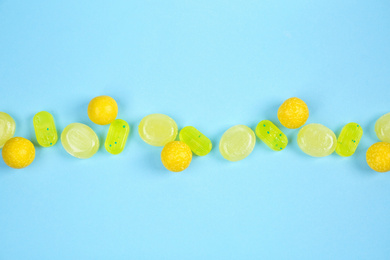 Photo of Delicious lemon candies on light blue background, flat lay