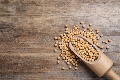 Photo of Scoop with chickpeas on wooden table, flat lay. space for text