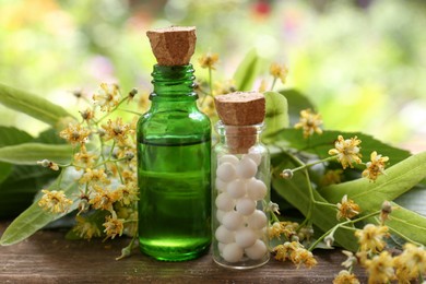 Photo of Tincture, bottle of homeopathic remedy and linden flowers on wooden table
