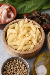 Raw pasta, bacon and fresh ingredients on light grey table