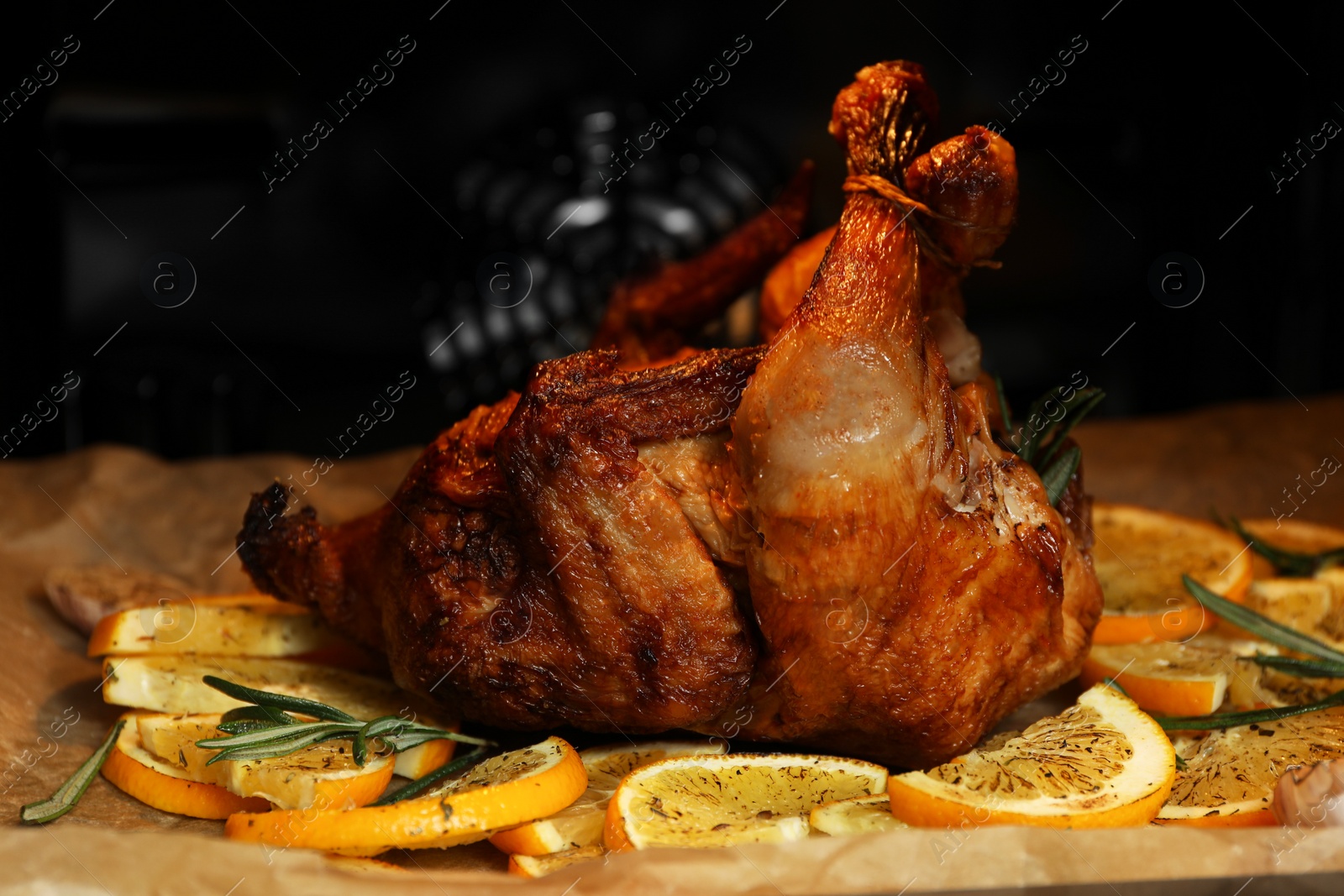 Photo of Cooked chicken with orange slices and rosemary on baking paper