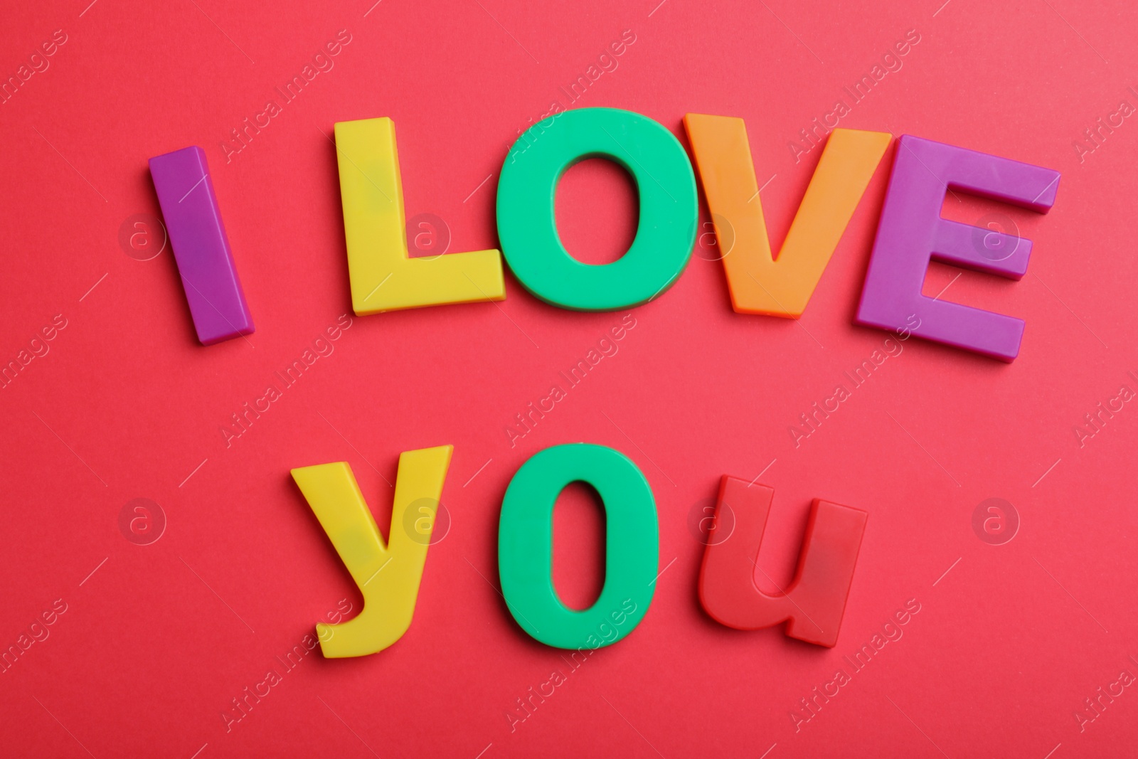 Photo of Phrase I Love You made of colorful letters on red background, flat lay