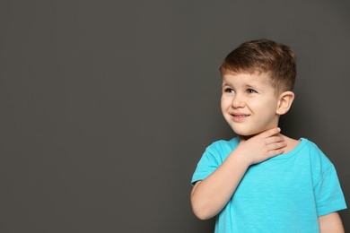 Cute boy suffering from cough on dark background. Space for text