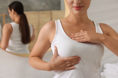 Photo of Woman doing breast self-examination in bathroom, closeup